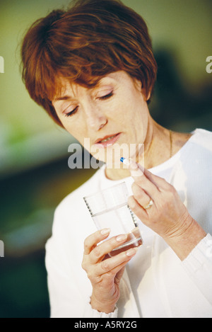 La prise de comprimé, Senior woman holding glass of water Banque D'Images