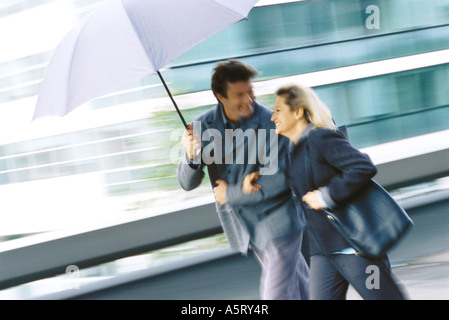 Mature couple walking under umbrella Banque D'Images