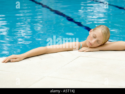 Young woman resting head on edge of pool Banque D'Images