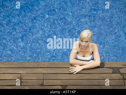 Jeune femme les bras au repos sur le bord de la piscine Banque D'Images