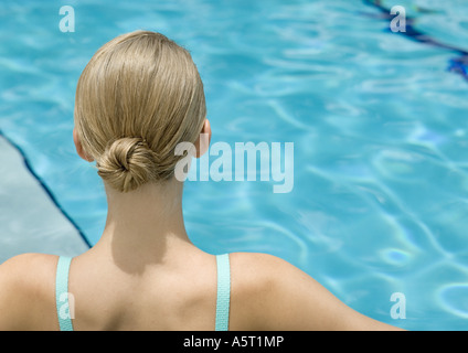 Jeune femme, vue arrière de la tête et des épaules, la piscine en arrière-plan Banque D'Images