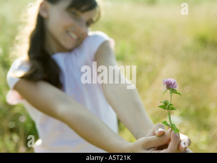 Girl holding out fleur, fleur en premier plan l'accent sur Banque D'Images