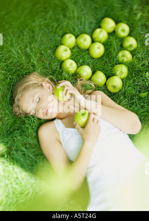 Femme couchée dans l'herbe, à côté de pommes disposées en forme de coeur Banque D'Images