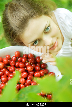 Woman holding bowl of cherries, smiling at camera Banque D'Images