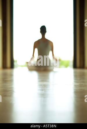 Cours de Yoga, woman sitting in lotus position, rétro-éclairé et de flou artistique Banque D'Images