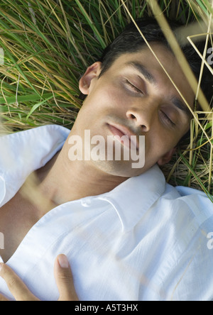 Man sleeping in tall grass, close-up Banque D'Images