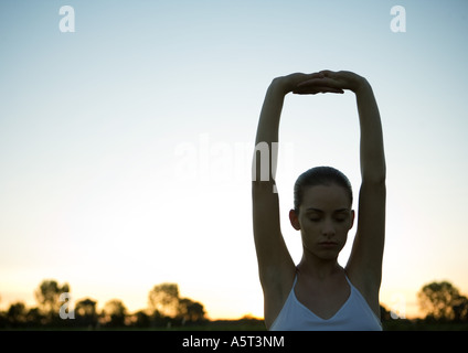 Woman stretching arms over head, rétroéclairé Banque D'Images