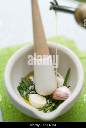 Mortier et pilon avec des herbes, l'huile d'olive et l'ail Banque D'Images