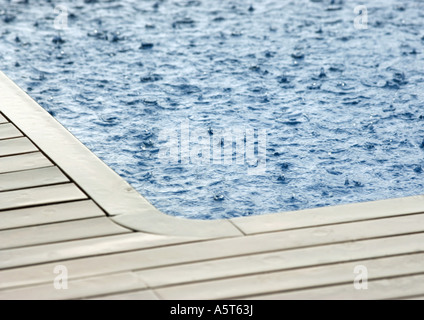 La pluie qui tombe sur la surface de la piscine Banque D'Images