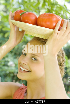 Woman holding bowl full de tomates sur le dessus de la tête