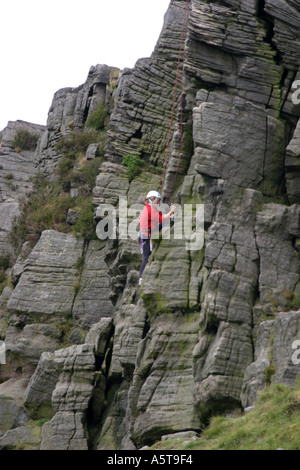 Alpinistes sur Windgather rochers sur le côté est du Peak District, Derbyshire, Angleterre. L'homme au haut des rochers est l'assurage d'un grimpeur sur le chemin vers le haut. Banque D'Images