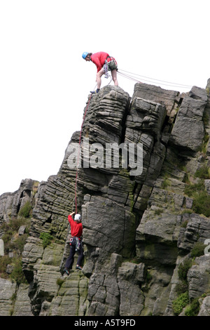 Alpinistes sur Windgather rochers sur le côté est du Peak District, Derbyshire, Angleterre. L'homme au haut des rochers est l'assurage d'un grimpeur sur le chemin vers le haut. Banque D'Images