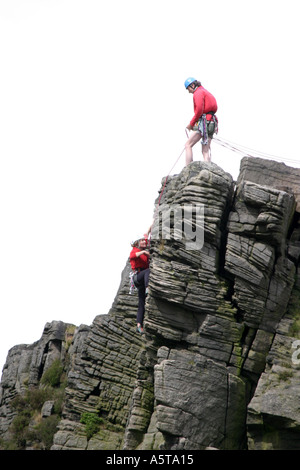 Alpinistes sur Windgather rochers sur le côté est du Peak District, Derbyshire, Angleterre. L'homme au haut des rochers est l'assurage d'un grimpeur sur le chemin vers le haut. Banque D'Images