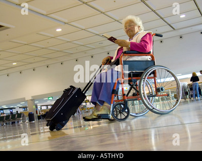 FAUTEUIL ROULANT DE L'AÉROPORT une femme âgée indépendante attend dans le hall de l'aéroport pour vérifier ses billets de voyage. Vacances avec une vieille dame Banque D'Images