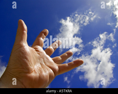 Homme part s'étendant jusqu'à un ciel bleu avec des nuages Banque D'Images