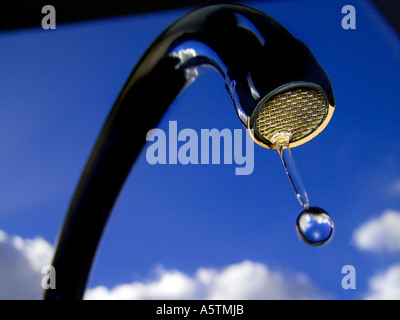 Robinet goutte-à-goutte EAU ENVIRONNEMENT Ciel clair de gouttes d'eau de robinet de cuisine vue à angle faible contre le soleil bleu ciel et nuages Banque D'Images