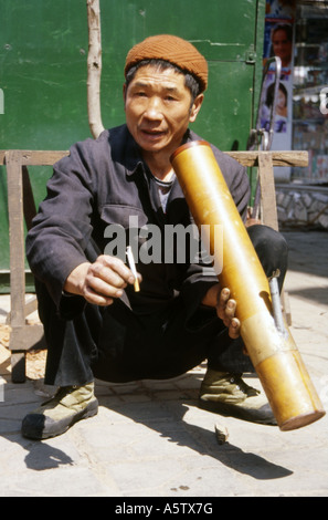 L'homme traditionnel local en veste bleu fumer une cigarette à travers une grande pipe du bambou dans la rue kunming Yunnan, Chine Banque D'Images