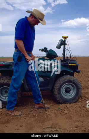 Agriculteur DANS LE CHAMP EN PRENANT des échantillons de sol à l'aide de technologies modernes comme l'ATV AVEC ORDINATEUR ET TÉLÉPHONE CELLULAIRE GPS / Texas Banque D'Images