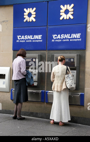 Les femmes qui prennent l'argent d'un distributeur automatique de billets Banque D'Images