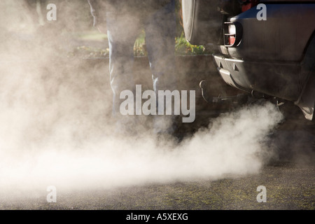 Nuage d'échappement d'une voiture. UK. La pollution et les vapeurs d'un véhicule. Homme debout derrière les nuages d'échappement. Banque D'Images