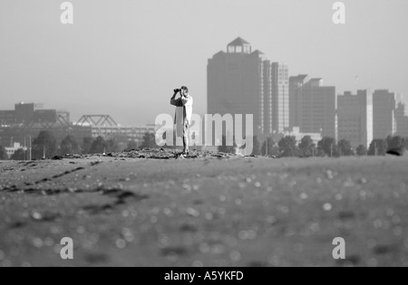 Man Standing on sand dune binoculars New Haven Connecticut Shoreline Banque D'Images