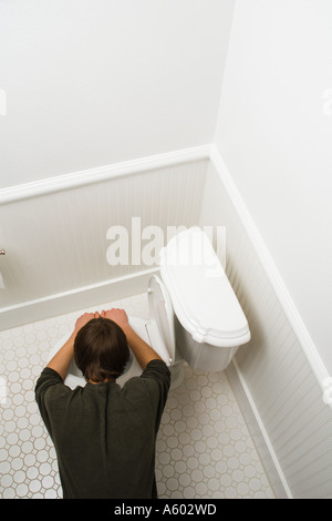 Vue supérieure de l'adolescent mâle se pencha sur toilettes être malade Banque D'Images