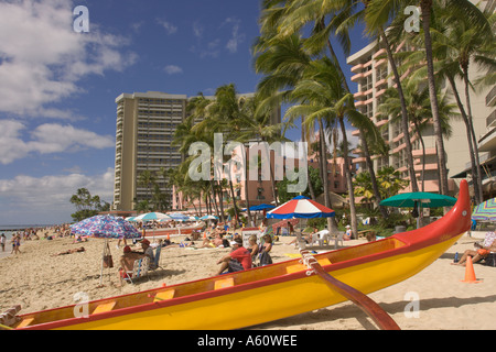 Afficher le long de la plage de Waikiki Outrigger Canoe rouge et jaune s'arrêta sur plage bleu ciel avec des nuages blancs de Honolulu Oahu Hawaii Banque D'Images