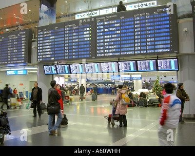 L'aéroport de Pékin, Chine. Les passagers de l'air à la recherche arrivée départ au hall central bulletin électronique avis conseil surveille Banque D'Images