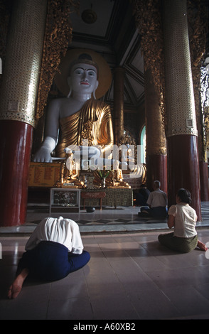 Tôt le matin, les fidèles bouddhistes prier dans un temple à l'intérieur de la Pagode Shwedagon de Rangoon, Birmanie complexe s Banque D'Images