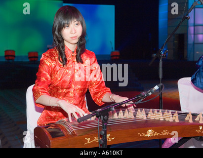 Chinois classique antique cithare musical instrument type le zheng, communément appelé le guzheng, joué par jeune femme Banque D'Images