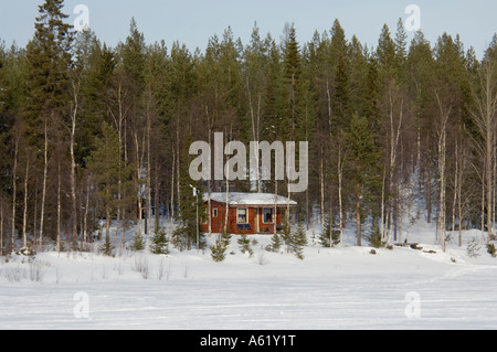 Maison de vacances log cabin dans la forêt le long de la rivière gelée, Luosto, Laponie, Finlande, Europe du Nord, de l'Arctique Banque D'Images