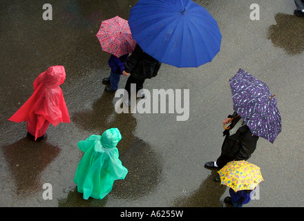 Spectateurs wearing rain ponchos et des parasols brave la pluie pour regarder la précession de La Passion à Chicago. Banque D'Images