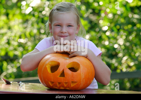 Une jeune fille heureuse est fier de la citrouille qu'elle a préparé pour l'Halloween Banque D'Images