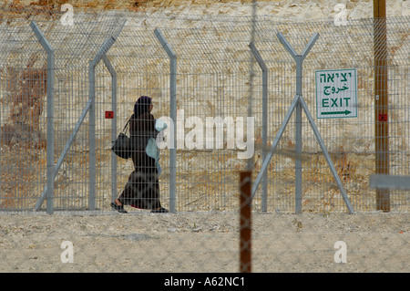 Une femme palestinienne traverse une clôture périphérique à un point de contrôle militaire israélien en Cisjordanie Banque D'Images