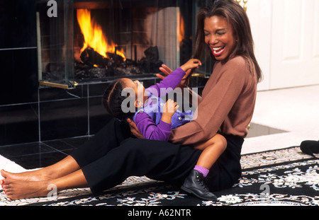 Black african american mother and daughter hugging à hme ensemble devant le foyer Banque D'Images