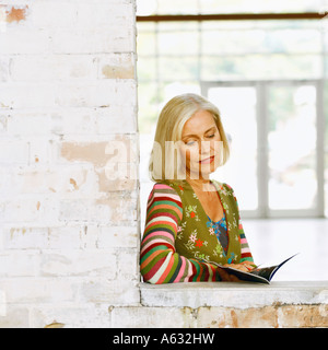 Portrait of a young woman reading a magazine Banque D'Images