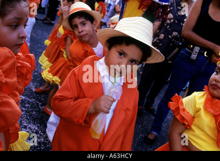 Garçon en veste orange, boire du jus d'orange, au défilé du carnaval des enfants, Veracruz, Mexique Banque D'Images