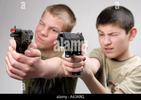 Deux jeunes garçons pointant leurs pistolets jouets à un ennemi caché Banque D'Images