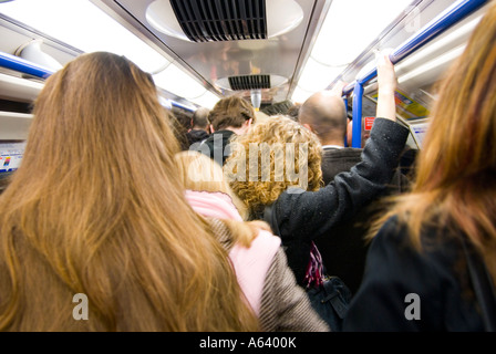 Les personnes voyageant pour travailler sur un chariot de métro surpeuplé pendant l'heure de pointe du matin, England UK Banque D'Images