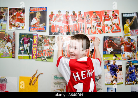 Jeune garçon supporter de football d'Arsenal en posant des affiches sur le mur de sa chambre London England UK Banque D'Images