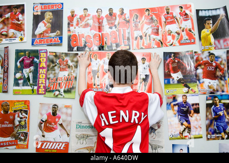 Jeune garçon supporter de football d'Arsenal en posant des affiches sur le mur de sa chambre, London, England, UK Banque D'Images