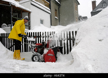 L'homme se déplace de la neige à l'aide d'une clôture de jardin souffleuse automatique à Oberwiesenthal, Erzgebirge, Saxe, Erz Monts Métallifères Banque D'Images