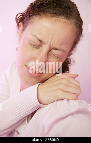 Jeune femme victime de la douleur de l'épaule. Aussi connu comme ayant une douleur dans le cou. Banque D'Images