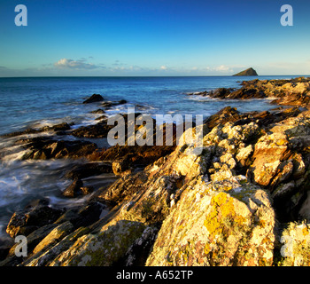 Belle aube lumière à wembury plage avec la mer tourbillonnant autour de la roches exposées et le Mew stone à l'horizon Banque D'Images