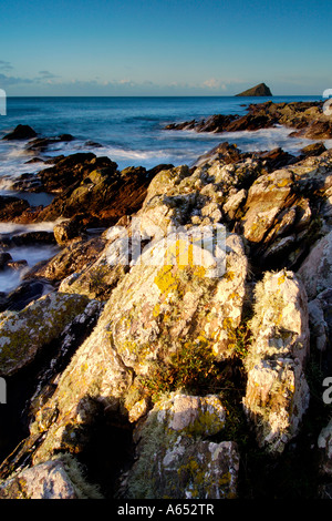 Belle aube lumière à wembury plage avec la mer tourbillonnant autour de la roches exposées et le Mew stone à l'horizon Banque D'Images