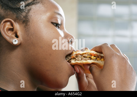 Onze ans, fille de manger un burger au fromage. Banque D'Images