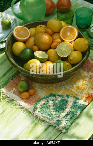 Close-up d'oranges et citrons limes avec bol en céramique verte dans le mat Banque D'Images