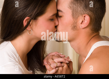 Jeune couple caucasien se tenant la main et partageant un doux baiser les yeux fermés, USA. Banque D'Images