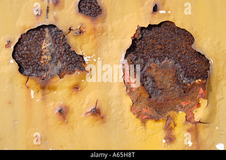 Deux taches de rouille gravement une surface en métal peint jaune Banque D'Images