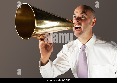 Balding middle-aged businessman shouting through megaphone Banque D'Images